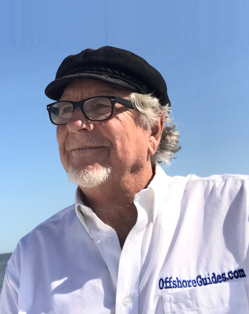 Man in an OffshoreGuides.com shirt standing on a boat with the ocean in the background