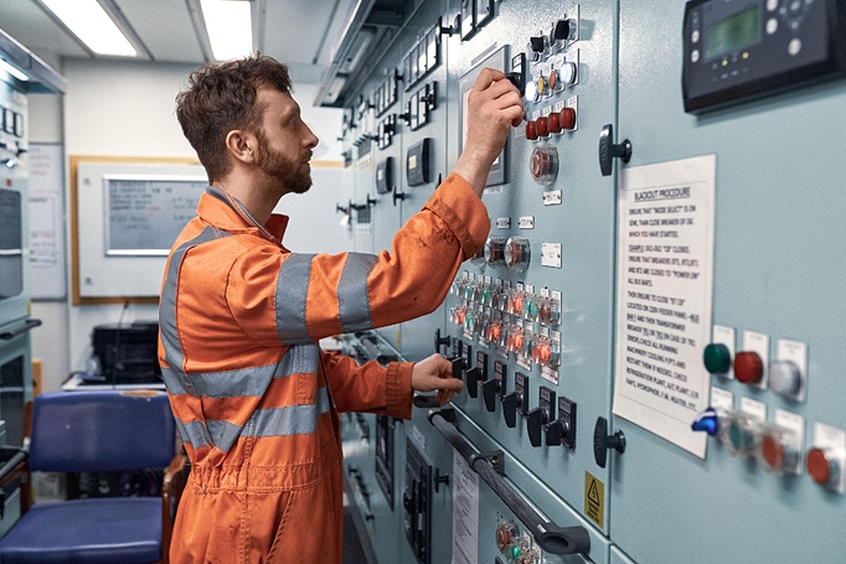 Offshore control room operator adjusting electrical control panels